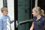 Boy holding door open for girl