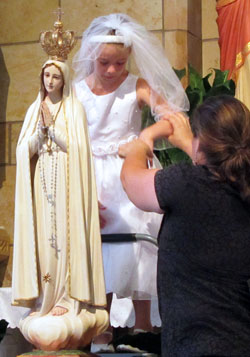 Ceirwen Abell is helped down after placing the newly gold-plated crown on the statue of Mary that overlooks the altar at St. Mary Church in Lanesville on May 6. (Submitted photo)