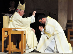 Transitional Deacon Jerry Byrd kneels at SS. Peter and Paul Cathedral in Indianapolis to receive a blessing from Bishop Christopher J. Coyne, apostolic administrator, prior to proclaiming the Gospel during a celebration of an Easter Vigil Mass on April 7. Bishop Coyne will ordain Deacon Byrd a priest on June 2 at the cathedral. (Photo by Sean Gallagher)