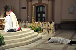 Deacon Jerry Byrd lies prostrate in prayer during the praying of the Litany of the Saints just prior to being ordained a priest on June 2 at SS. Peter and Paul Cathedral in Indianapolis. Also kneeling in prayer are Father Patrick Beidelman, left, archdiocesan director of liturgy; Bishop Christopher J. Coyne, apostolic administrator; and priests who minister at parishes in central and southern Indiana. (Photo by Sean Gallagher)