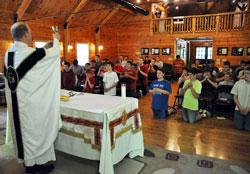 More than 40 junior high and high school-age boys kneel in prayer while Father Patrick Beidelman elevates a chalice during a June 13 Mass at the Future Farmers of America Leadership Center in Johnson County. The Mass was part of Bishop Bruté Days, a vocations camp and retreat experience sponsored by Bishop Simon Bruté College Seminary in Indianapolis, where Father Beidelman serves as vice rector. (Photo by Sean Gallagher)