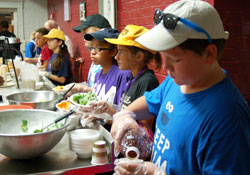 Brian Allspaw, right, an eighth-grader at St. Lawrence School in Indianapolis; Mia Pursell, a seventh-grader at Westlane Middle School in Indianapolis; Marta Schmitz, a sixth-grader at Immaculate Heart of Mary in Indianapolis; and Janie Gleaves, a seventh-grader at Immaculate Heart of Mary School, serve drinks, salad and fruit at the Cathedral Soup Kitchen in Indianapolis on June 19. The group traveled to the soup kitchen as part of their IntenCity Summer Service Camp. (Photo by Alison Graham)