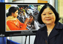 Catholic Relief Services president and chief executive officer Carolyn Woo, a former Hoosier, poses for a photograph on June 21 in front of a poster featuring the lifesaving work of the U.S. Church’s international humanitarian aid organization. Woo was a keynote speaker at the Catholic Media Conference in Indianapolis. (Photo by Mary Ann Garber)