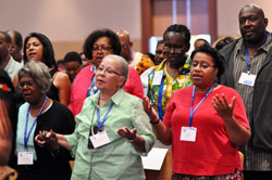 Opal Easter-Smith, from left, Margo Butler and Adrienne Curry from the Archdiocese of Chicago pray during the National Black Catholic Congress Mass on July 20 in Indianapolis. During the congress, Benedictine Father Cyprian Davis of Saint Meinrad Archabbey in St. Meinrad was honored with a lifetime achievement award. (Photo by Mary Ann Garber)