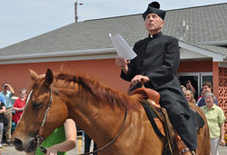 Father Paul Landwerlen, administrator of St. Vincent de Paul Parish in Shelby County, reads a proclamation about the faith community’s 175-year history after riding a horse onto its grounds on June 24 during an event to kick off a series of celebrations of its anniversary. St. Vincent’s founding pastor, Father Vincent Bacquelin, rode on horseback from the Shelby County parish to minister to Catholics throughout central and eastern Indiana. (Submitted photo by Jennifer Lindberg)