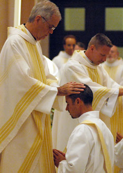 Father David Lawler, left, ritually lays hands upon transitional Deacon Christopher Wadelton on June 27, 2009 in SS. Peter and Paul Cathedral in Indianapolis. Father Lawler had previously served as pastor of now-Father Wadelton and has influenced his approach to priestly life and ministry. (File photo by Sean Gallagher)