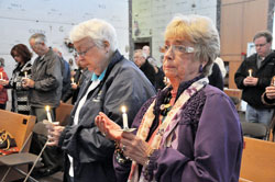 Good Shepherd parishioner Mary Jane Mattingly of Indianapolis, left, and St. Lawrence parishioner Patricia Beaupre of Indianapolis hold lighted candles as they pray during an All Souls Day Mass on Nov. 2 at the Calvary Cemetery Mausoleum Chapel in Indianapolis. They are widows and longtime friends. (Photo by Mary Ann Garber)