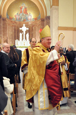 While processing out of SS. Peter and Paul Cathedral in Indianapolis, Archbishop Joseph W. Tobin blesses members of the congregation after the Dec. 3 Mass during which he was installed as the sixth archbishop of Indianapolis. Accompanying him are permanent Deacon Russell Woodard, left, and transitional Deacon John Kamwendo. (Photo by Mary Ann Garber)