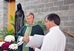 Father Bernard Cox, pastor of Mary, Queen of Peace Parish in Danville, blesses a new bronze statue of Our Lady of Peace during a Mass on Oct. 28 at the church in Danville. Parishioner Phil Schneider assisted him with the ceremony. (Photo by Mary Ann Garber)