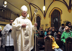 Archbishop Joseph W. Tobin processes into St. Anthony Church in Indianapolis on Dec. 12 to celebrate a Mass in Spanish marking the feast of Our Lady of Guadalupe. Behind him is Ford Cox, executive assistant to the archbishop and liaison for episcopal affairs. (File photo by Sean Gallagher)