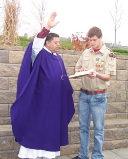 Father Juan Valdes, administrator at St. Mary Parish in Lanesville, blesses the new prayer garden on Dec. 2 on the parish’s grounds during a dedication ceremony. He is assisted by Eagle Scout Josh Hublar, a member of the parish, who built the prayer garden for his Eagle Scout project. (Submitted photo by Leslie Lynch)