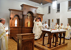 Archbishop Joseph W. Tobin, center, blesses the renovated chapel of Bishop Simon Bruté Seminary in Indianapolis during a Jan. 28 Mass. One feature of the renovated chapel is the altar piece, or reredos, that stands behind the chapel’s altar. The reredos was designed by Eric Atkins, archdiocesan director of management services. (Photo by Sean Gallagher)