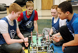 Bishop Chatard High School students Joe Bormann, left, Jacob Mack, Courtney Thompson and Robert Dooley work on one of the robots that their team built for the Indianapolis VEX Robotics Championship in Indianapolis on Jan. 19-20. Four teams from Catholic schools in the archdiocese finished in the top 10 at the competition. (Photo by John Shaughnessy)