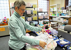 Archdiocesan Birthline coordinator Jená Hartman examines infant clothing that is available to help new mothers and their babies who desperately need emergency assistance. (Photo by Mary Ann Garber)