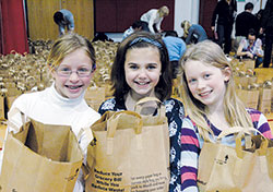 Mary Sowinski, left, Lillian Henninger and Maggie McHugh pose for a photo after filling grocery bags with food items for families in need. The girls were part of the North Side Easter Basket Project at St. Matthew the Apostle Parish in Indianapolis on March 24. A day later, 600 families received the ingredients to help them have an Easter feast. (Photo by John Shaughnessy)