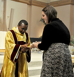 Rachel Worden, a young adult member of St. John the Evangelist Parish in Indianapolis, receives her faith community’s holy oils from transitional Deacon John Kamwendo during the annual archdiocesan chrism Mass celebrated on March 26 at SS. Peter and Paul Cathedral in Indianapolis. (Photo by Sean Gallagher)