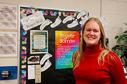 Erica Heinekamp poses by the Prayer Wall she has created for her fourth-grade students at St. Susanna School in Plainfield. Heinekamp is one of many young adults in the archdiocese eager to be a part of community while nurturing her life of faith. (Photo by John Shaughnessy)