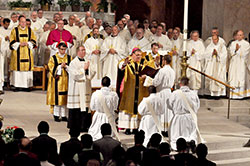 With transitional deacons, dozens of priests and Bishop Christopher J. Coyne standing behind him, Archbishop Joseph W. Tobin prays the prayer of consecration during a May 18 ordination Mass at SS. Peter and Paul Cathedral in Indianapolis. Kneeling before Archbishop Tobin are transitional Deacons Martin Rodriguez, left, John Kamwendo and Douglas Marcotte, whom he ordained as priests during the liturgy. (Photo by Sean Gallagher)