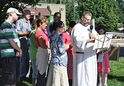 Domincan Father Simon Michalski, second from right, leads a prayer vigil as it is broadcast live on July 11 at a Planned Parenthood facility in Bloomington. Monica Seifker, center, coordinator of the vigil broadcast ministry, joins him in prayer. (Photo by Natalie Hoefer)