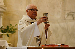 In this file photo, retired Father Clifford Vogelsang elevates a chalice during an April 2010 Mass in the Blessed Sacrament Chapel at SS. Peter and Paul Cathedral in Indianapolis. (File photo by Sean Gallagher)