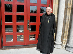 Retired Benedictine Archabbot Bonaventure Knaebel, 94, stands at the main doors of the Archabbey Church of Our Lady of Einsiedeln, the church of Saint Meinrad Archabbey in St. Meinrad, on July 17. (Photo by Sean Gallagher)