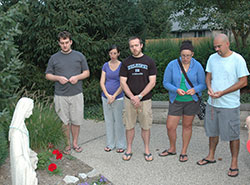 Hoping to build a faith community and a social connection among their peers, young adult members at St. Michael Parish in Greenfield got together twice a month this summer to pray the rosary in front of a shrine of the Blessed Mother near the parish church. Vincent Fuller, left, Katherine Seibert, Scott Seibert, Renee Odum and Shane Odum pray the rosary on the evening of Aug. 7. (Photo by John Shaughnessy)