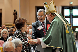 Ann and Joseph Wohlhieter of St. Barnabas Parish in Indianapolis share a laugh with Archbishop Joseph W. Tobin as he gives them a gift to celebrate their 63rd wedding anniversary at the Golden Jubilee Mass celebrated at SS. Peter and Paul Cathedral in Indianapolis on Sept. 22. (Photo by Natalie Hoefer)