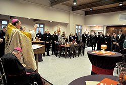 Archbishop Joseph W. Tobin raises his hands in prayer on Oct. 21 while blessing the new dining hall and dormitory of Bishop Simon Bruté College Seminary in Indianapolis. Archbishop Emeritus Daniel M. Buechlein attended the ceremony. The new dining hall is named after him. (Photo by Sean Gallagher)