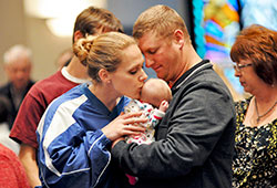 A mother kisses her child during a December 2012 Mass celebrated at Our Lady of the Greenwood Church in Greenwood. The “10 Things” resource says that Catholics want to work with all people of good will to build a “civilization of love.” (File photo by Mary Ann Garber)