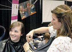 Paige Hicks, left, of the Diocese of Owensboro, Ky., is pictured with stylist Alice Hannon getting a haircut on Nov. 21. Paige was one of 40 youths at the National Catholic Youth Conference who signed up to have 10 inches of her hair cut off for “Locks of Love,” a program that provides wigs for financially disadvantaged children who have lost their hair because of a medical condition. (Photo by John Shaughnessy)