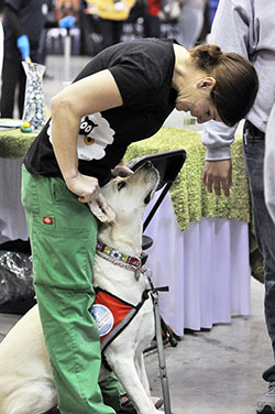 After performing a comedy routine on stage on Nov. 23 in an exhibit hall, comedian Judy McDonald pays some attention to her service dog, Daisy, at her booth at the National Catholic Youth Conference at the Indiana Convention Center in Indianapolis. (Photo by Natalie Hoefer)