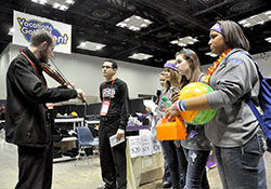 Transitional Deacon Daniel Bedel, a member of St. John the Evangelist Parish in Enochsburg, left, plays the violin on Nov. 22 for Guillermo Caballero, second from left, a seminarian of the Diocese of Little Rock, and teenage participants at the National Catholic Youth Conference held at the Indiana Convention Center and Lucas Oil Stadium in Indianapolis. (Photo by Sean Gallagher)