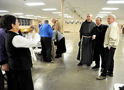 Linda Loesch, left, a member of St. Mary-of-the-Knobs Parish in Floyd County, takes a photo on Nov. 29 at Our Lady of Perpetual Help Parish in New Albany of Conventual Franciscan Father Ken Birch of Mount St. Francis, Archbishop William E. Lori of Baltimore and Ralph Nordhoff, a member of St. Michael Parish in Bradford. (Photo by Sean Gallagher)