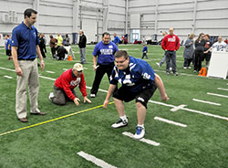 Special Olympian Bradley Johnson of Whiteland completes a jump in the broad jump portion of a National Football League-like combine event for athletes with developmental disabilities on Feb. 22 at the Indianapolis Colts practice facility in Indianapolis. Assisting him are, from left, former Indianapolis Colt Jim Sorgi, a member of St. Susanna Parish in Plainfield; and two members of the Knights of Columbus, Dennis Gochoel, a member of St. Simon the Apostle Parish in Indianapolis; and Pat Rondinella, a member of St. Malachy Parish in Brownsburg. (Photo by Sean Gallagher)