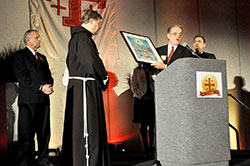 Mike LeCuyer, second from right, regional chairman of the Franciscan Foundation for the Holy Land and a member of St. John Vianney Parish in Fishers, Ind., in the Lafayette Diocese, presents a gift to Franciscan Father Peter Vasko at the J.W. Mariott hotel in Indianapolis during a March 22 foundation fundraising dinner, which in part celebrated the 20th anniversary of the establishment of the foundation. Looking on are dinner organizers Mike Hirsch, left, and Richard Sontag, right, both members of St. Luke the Evangelist Parish in Indianapolis. (Photo by Sean Gallagher)