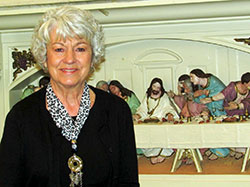 Mary Drake poses in front of a relief sculpture of the Last Supper at Prince of Peace Parish in Madison in this April 6 photo. Drake returned to the Church after 51 years, in part through the invitation of a friend to go to Mass and join a small church group. (Submitted photo)