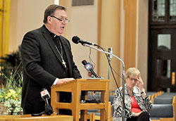 Archbishop Joseph W. Tobin speaks during a May 21 press conference held at SS. Peter and Paul Cathedral in Indianapolis in which he announced decisions regarding the Connected in the Spirit planning process for the four metropolitan Indianapolis deaneries. Archdiocesan chancellor Annette “Mickey” Lentz, right, looks on during the press conference. (Photo by Sean Gallagher)