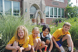 Several members of the Earth Council at St. Thomas Aquinas School in Indianapolis pose for a photo in a garden at the school, which was named a 2014 “Green Ribbon School” by the U.S. Department of Education. Reese Sochacki, left, Maisie McMahon, Maggie Gonzalez and Hank Fleetwood helped plant flowers in the garden. (Photo by John Shaughnessy)