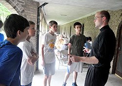 Newly ordained Father David Marcotte speaks on June 18 at Bishop Simon Bruté College Seminary in Indianapolis with Gabe Ochoa, left, Nathan Gramman, Mateo Gonzalez and Aaron Robinson, all members of SS. Francis and Clare of Assisi Parish in Greenwood. Father Marcotte, who will soon begin ministry as associate pastor of SS. Francis and Clare, spoke with the teenage boys during Bishop Bruté Days, the college seminary’s annual camping and retreat event for young men open to the idea that God might call them to the priesthood. (Photo by Sean Gallagher)