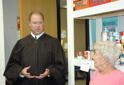 Judge David Certo of the Indianapolis Community Court visits with volunteers at the Officer David S. Moore Foundation Food Pantry, one of the court’s many efforts to help people who have committed non-violent, non-sexual crimes turn around their lives. Marsha Fecht, a volunteer from St. Patrick Parish in Indianapolis, listens to the judge. (Photo by John Shaughnessy)