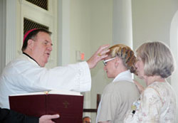 Archbishop Joseph W. Tobin anoints Kimberly Stewart as she receives the sacrament of confirmation during a Mass that the archbishop celebrated on June 29 at the Indiana Women’s Prison in Indianapolis. Kimberly’s mother, Theresa Stewart, rests her hand on her daughter’s shoulder. (Photo by John Shaughnessy)