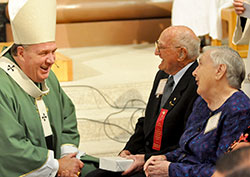 Howard and Geraldine Estes, members of St. Teresa Benedicta of the Cross Parish in Bright, share a laugh with Archbishop Joseph W. Tobin after receiving a gift from the archdiocese during the Golden Wedding Jubilee Mass at SS. Peter and Paul Cathedral in Indianapolis on Sept. 21. The couple has been married for 70 years. (Photo by Natalie Hoefer)