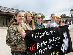 Clarie Pfister, left, a member of St. Patrick Parish in Terre Haute; John Paul II Catholic High School student Julianna Gallion; Celine Mitchell, a member of St. Patrick Parish; John Paul II Catholic High School student Erin Pfister; and Cassie Mitchell, a member of St. Patrick Parish, hold a banner during the Life Chain in Terre Haute on Oct. 5. (Submitted photo by Tom McBroom)