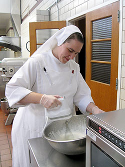 Franciscan Sister Madeleine Schumacker prepares a dessert on Sept. 23 in the kitchen of the Mishawaka, Ind., motherhouse of her religious community, the Sisters of St. Francis of Perpetual Adoration. Previously a member of St. Louis Parish in Batesville, Sister Madeleine professed perpetual vows earlier this year. (Submitted photo)