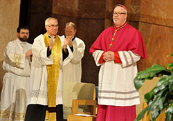 Seminarian Michael Dedek, left, Father Todd Riebe and Father Patrick Beidelman joined the rest of the congregation at SS. Peter and Paul Cathedral in Indianapolis on Jan. 14 in giving a standing ovation to Bishop Christopher J. Coyne during an Evening Prayer liturgy in which Catholics across central and southern Indiana bid farewell to the former auxiliary bishop. Bishop Coyne will be formally installed on Jan. 29 as shepherd of the Diocese of Burlington, Vt.  (Photo by Sean Gallagher)