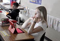 Light from an iPad screen shines on Lydia Gigrich, left, an eighth grade student at St. Louis School in Batesville on Jan. 8. The Batesville Deanery school is a year and a half into having all of its students use iPads in its classrooms and for homework assignments. Sitting next to Lydia is eighth grader Alex Greers. (Photo by Sean Gallagher) 