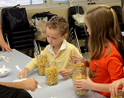Fourth-grade students Jack Bryant and Sophia Denison of Holy Family School in New Albany help to create “soup in a jar” to benefit families in need. (Submitted photo)