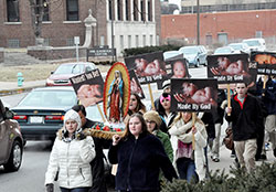 Participants in the archdiocesan solemn observance of the legalization of abortion pray the rosary with a statue of Our Lady of Guadalupe and signs along Meridian Street in Indianapolis during a pro-life procession on Jan. 22. (Photo by Natalie Hoefer)