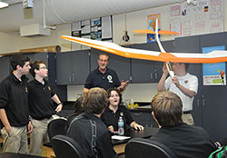 Tom Beckenbauer, middle, discusses the model plane built by Spencer Leonard, holding the model, during a Catholic Aviation Association Cupertino Club meeting at St. Theodore Guérin High School in Noblesville, Ind., in the Lafayette Diocese on Nov. 6, 2014. (Photo by Natalie Hoefer)