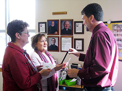 Linda Augenstein, left, and Kathy Kaler, both members of St. Jude Parish in Indianapolis, speak about vocations on Feb. 15 with Bil Danner, the parish’s director of adult faith formation, at St. Jude’s “vocations station” in the narthex of its church. Augenstein helps lead St. Jude’s vocations committee, which maintains the vocations station. (Submitted photo)